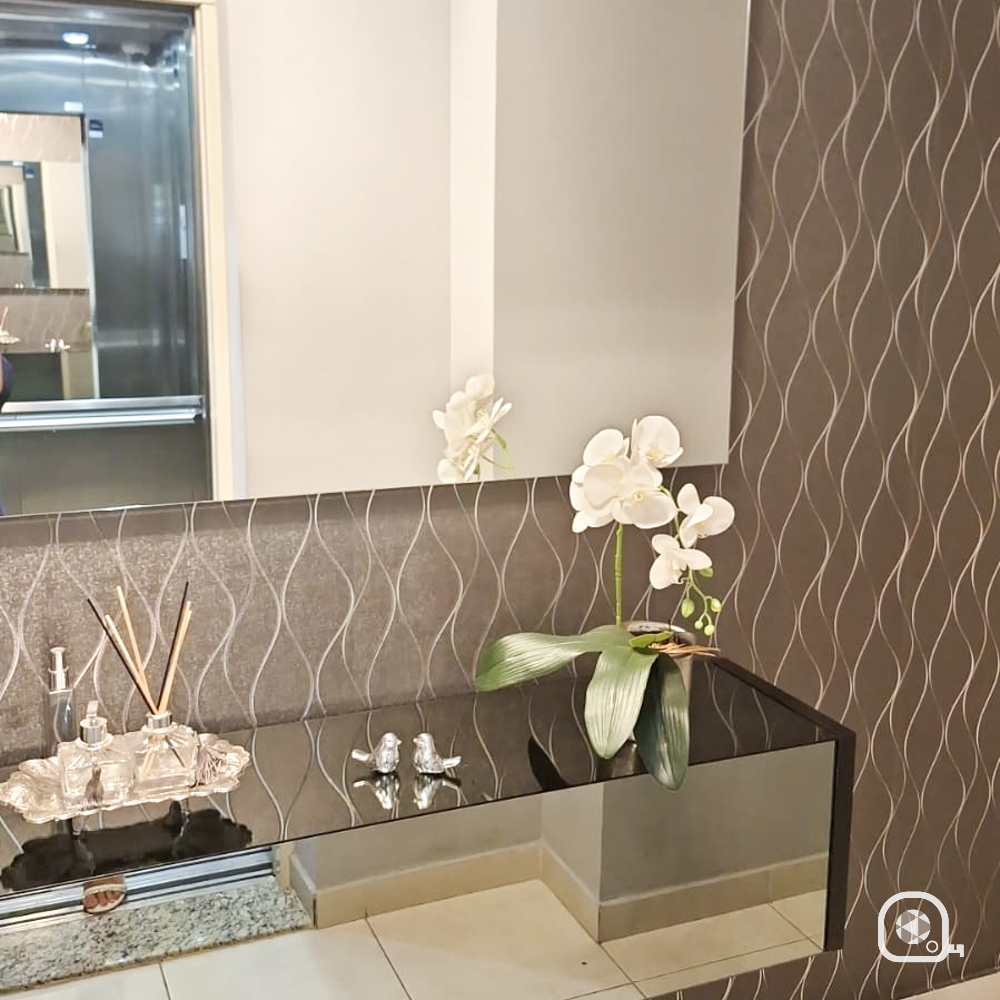 Lavabo com papel de parede texturizado ondulado em marrom e bancada com detalhes decorativos.